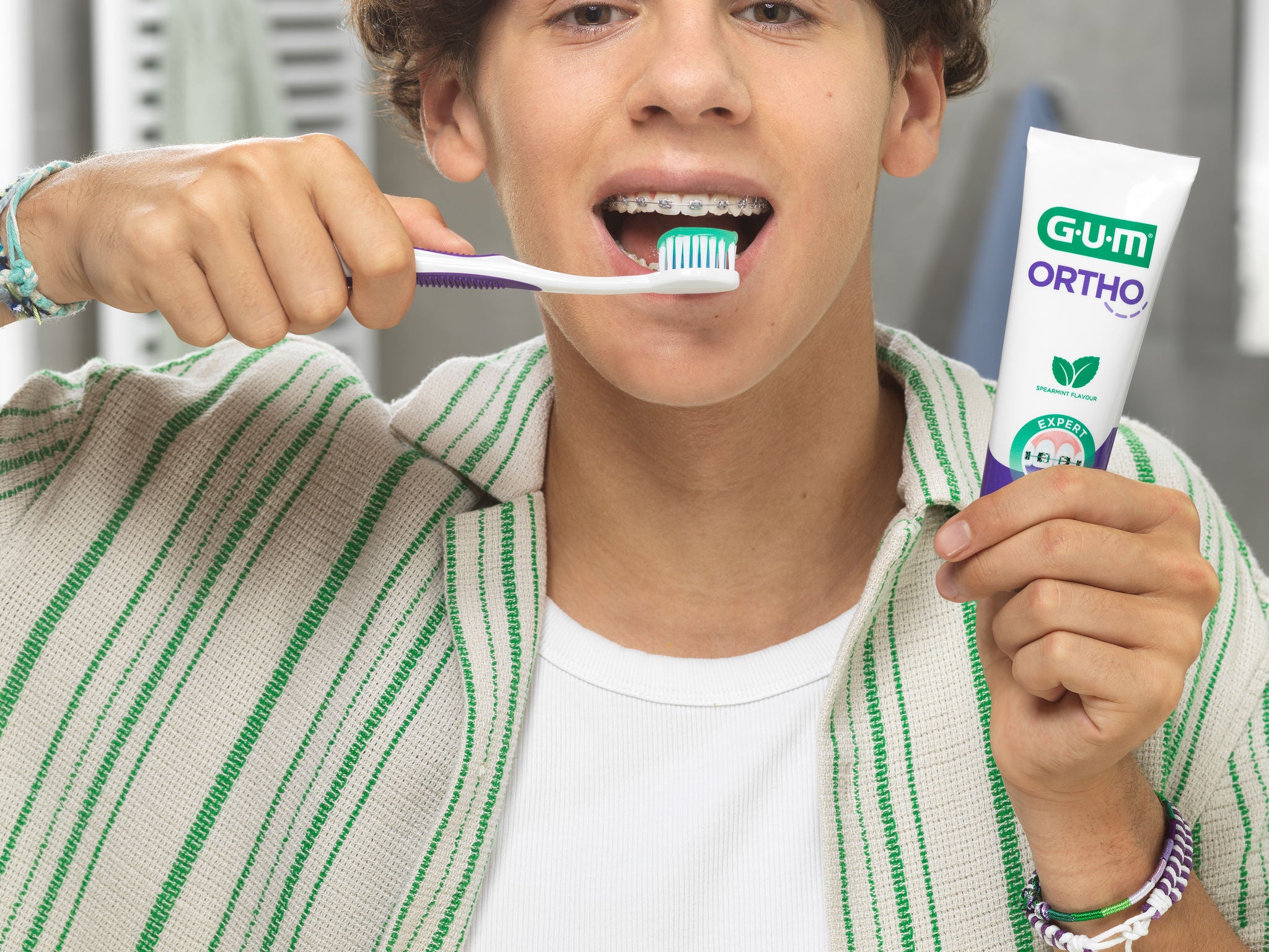Teenager is brushing teeth with the GUM ORTHO Toothbrush and GUM ORTHO Toothpaste