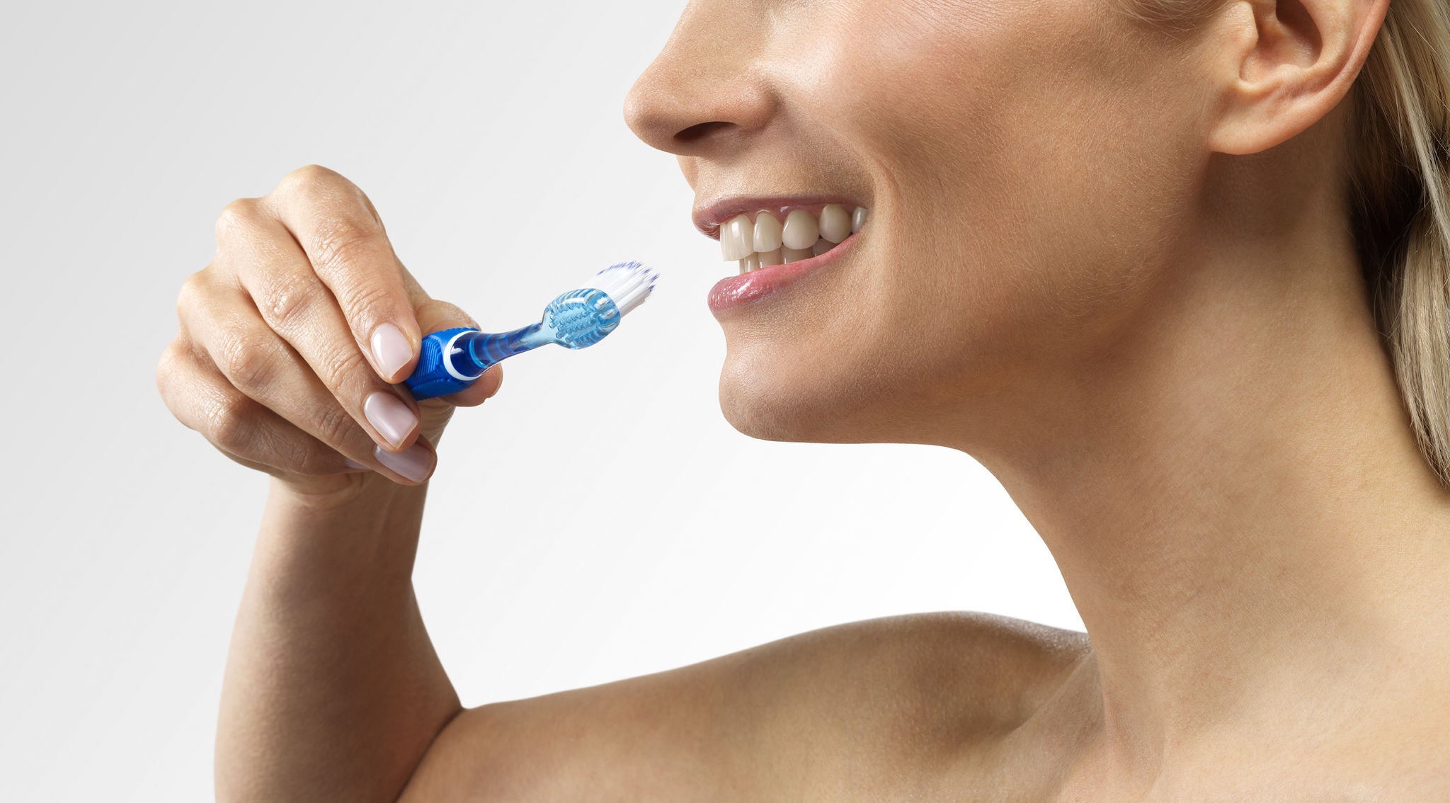 Woman smiling while is showing how to use the GUM PRO toothbrush