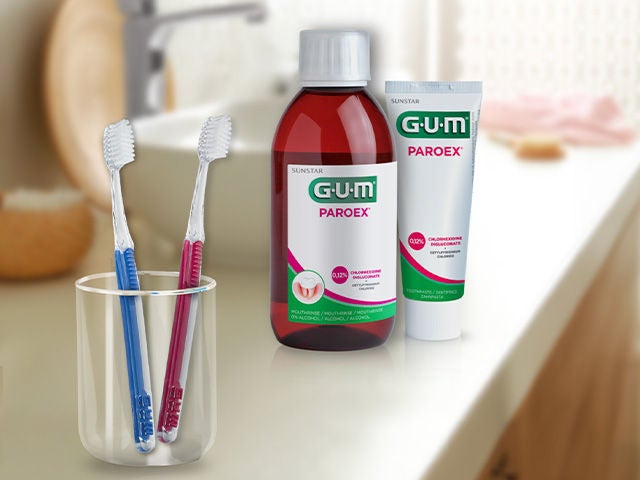 GUM PAROEX Intensive Action mouthwash and toothpaste, GUM Post-Operation toothbrushes in 2 colours placed in a glass in the bathroom