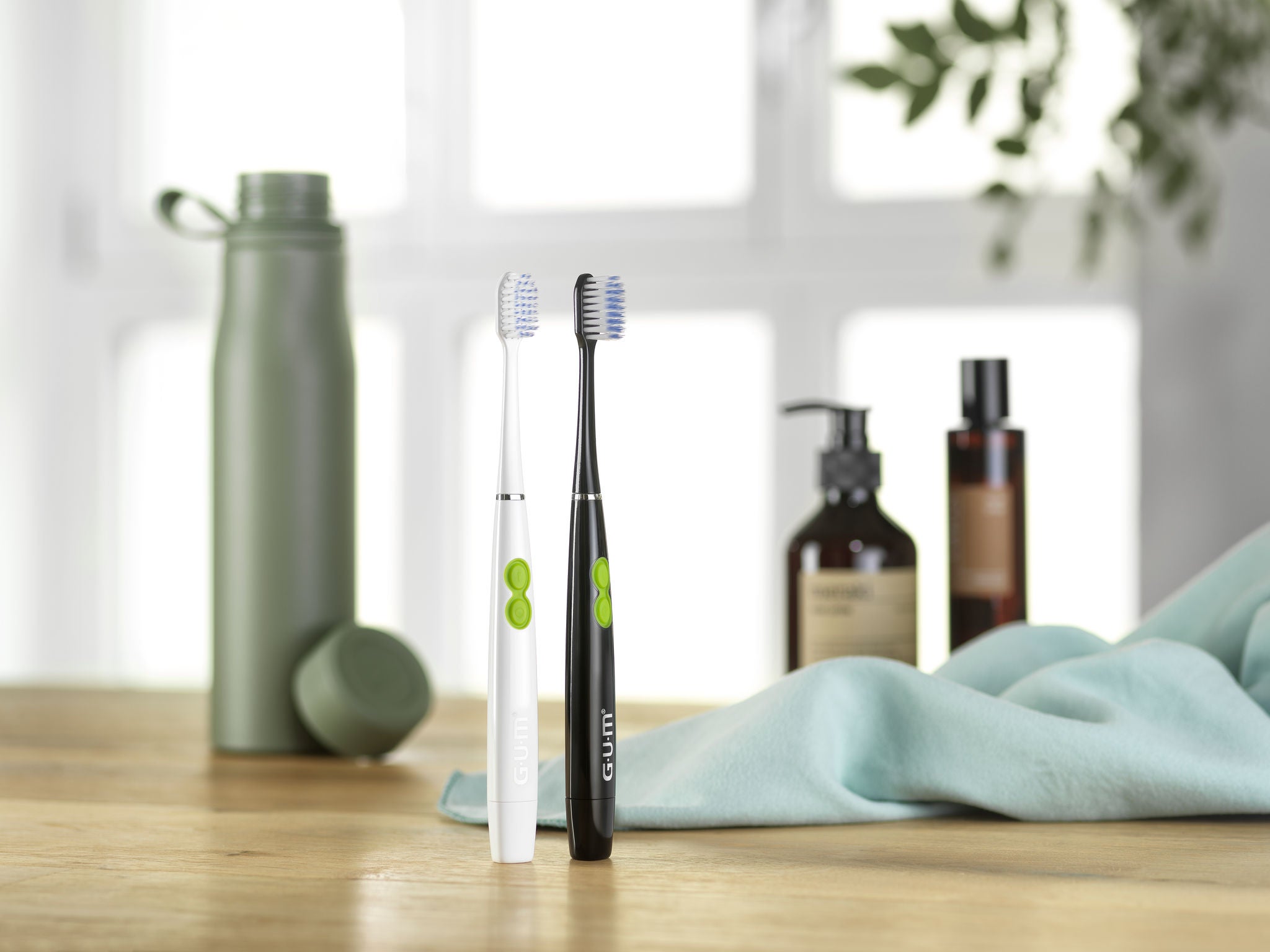 2 GUM SONIC DAILY Toothbrushes black and white along with beauty accessories and a water bottle in the background