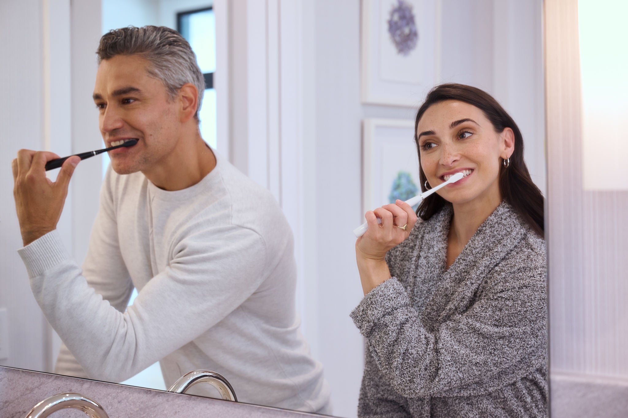 Man och kvinna borstar sina tänder med batteritandborsten med soniska vibrationer GUM SONIC DAILY