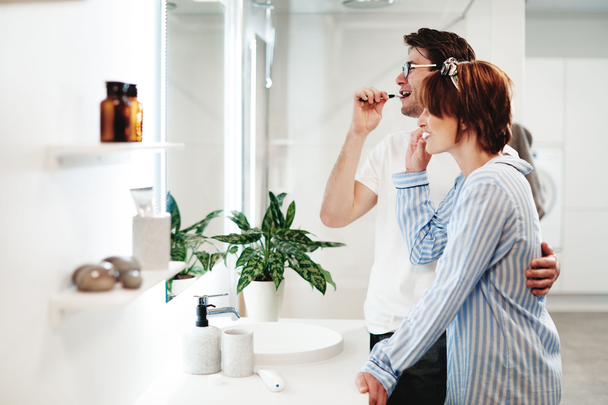 Coppia sorridente in bagno per la loro routine di igiene orale, mentre il ragazzo si lava i denti con il GM sonic daily Battery Toothbrush, la ragazza tiene in mano i GUM SOFT PICKS Interdental avanzato