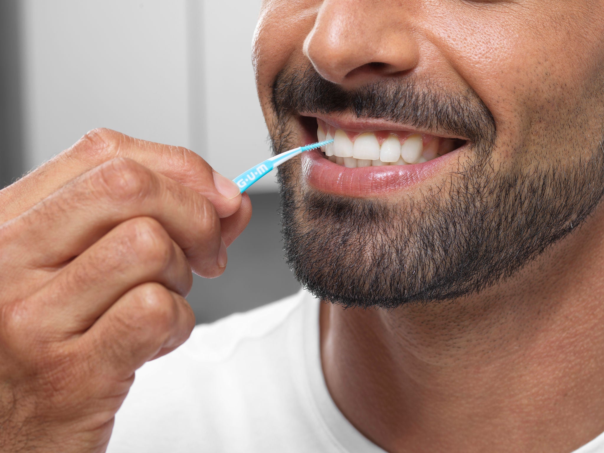 Man is cleaning between teeth with GUM SOFT-PICKS PRO interdental brush 
