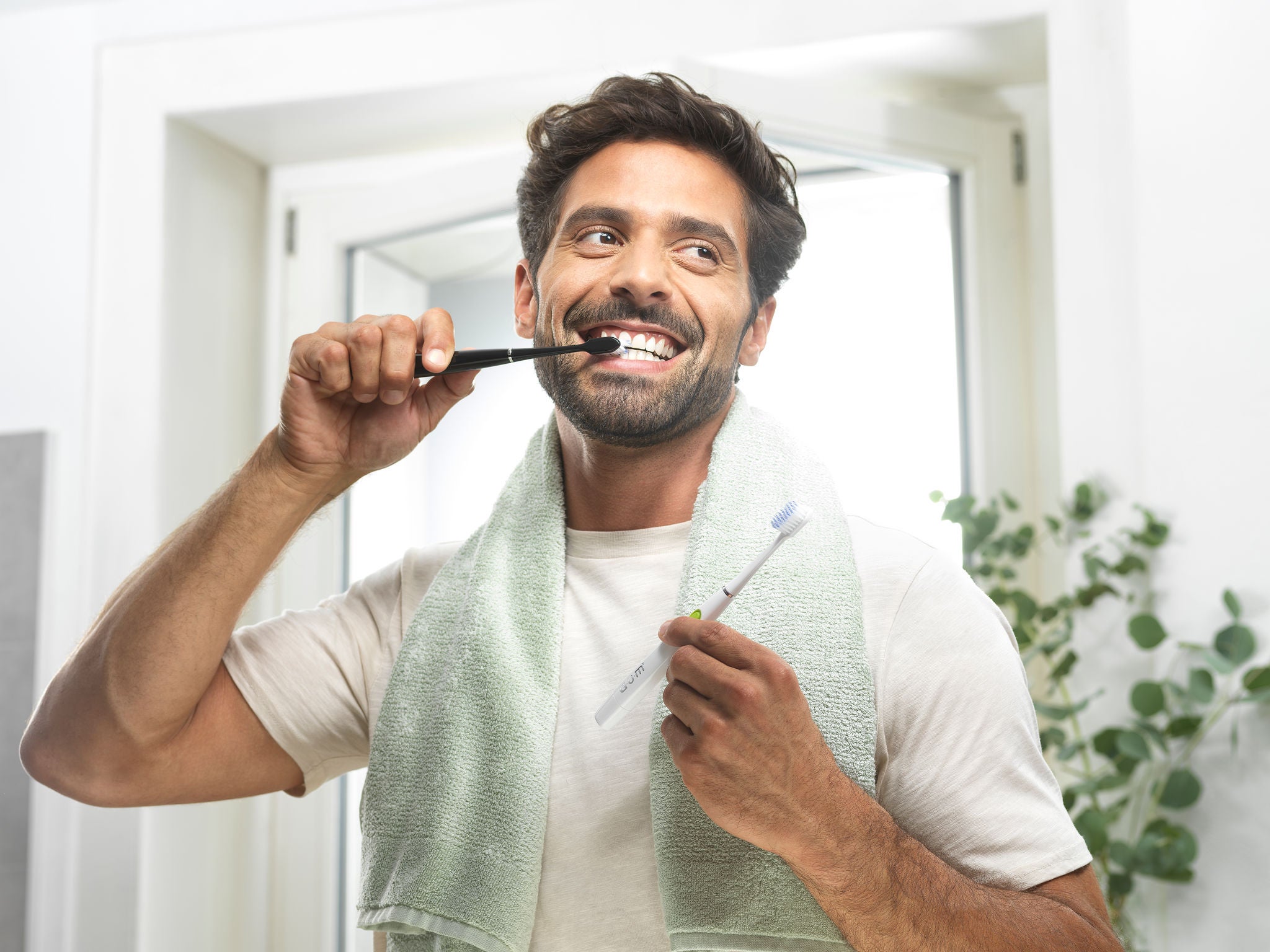 a smiling man is choosing the GUM SONIC Battery Electric toothbrush in black version to brush his teeth 