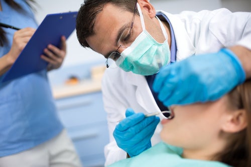 dentista con mascherina visita la bocca di un bambino
