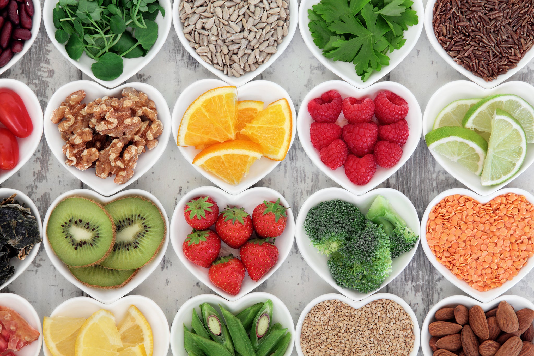 Super food selection for health diet in porcelain bowls over distressed wooden background.