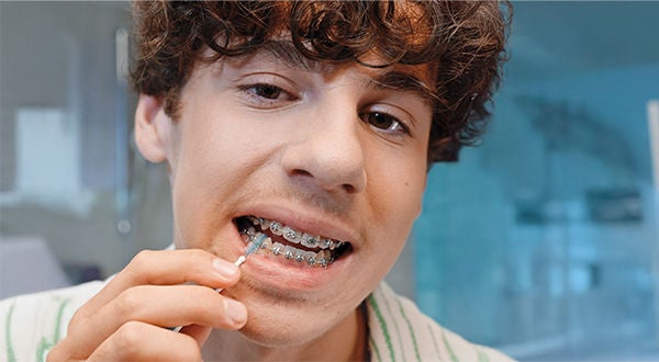 In-Context-GUM-TRAV-LER-Boy-With-Brackets-Using-Interdental-Brush-600x330px